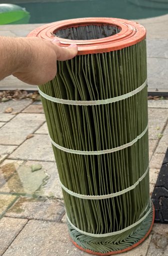 Pool filter cartridge stained green with algae before service