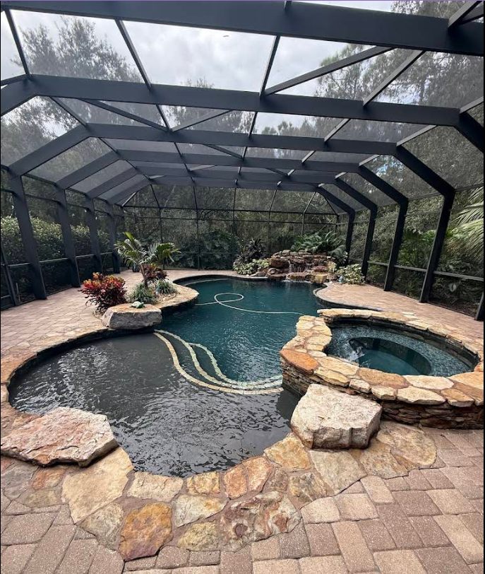Florida screened-in pool with hot tub spillover and stone surround, maintained by Sundays Pools